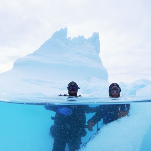 David Gruber (left) and John Sparks (right) under the ice in the waters off eastern Greenland. Although the water never touched any of their skin because of the outer rubber suit, they poured hot water or tea into their gloves to get a little extra time in the water before their fingers became immobile.